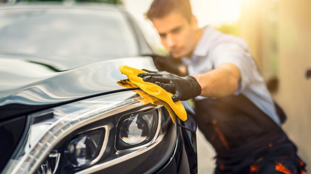 Detailer hand-waxing a car panel