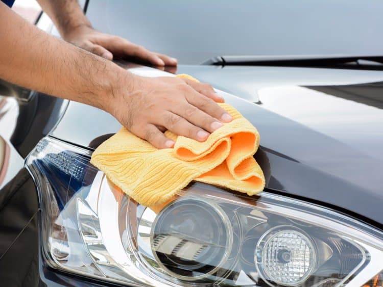 Hand wiping down a headlight and fender